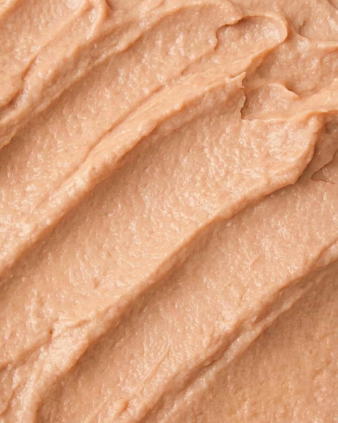 Creamy beige almond butter spread with a smooth, textured finish, ideal for healthy snacking or baking.