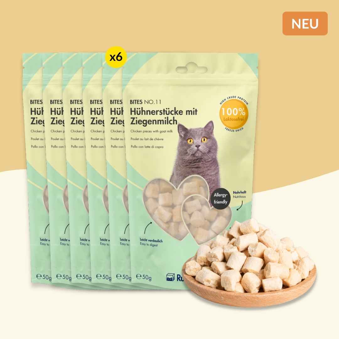 Sechs Packungen RumbleBox Bites No. 11 Hühnerstücke mit laktosefreier Ziegenmilch neben einer Schale mit Snackwürfeln.